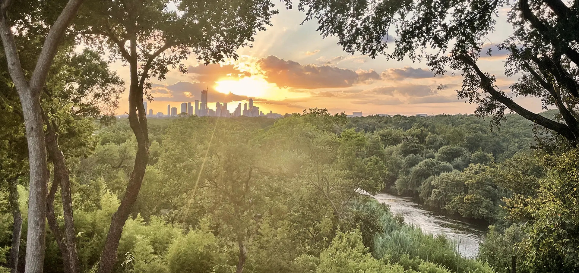 Wide panorama of the Austin skyline, the Colorado River, and the parkland surrounding The Observatory