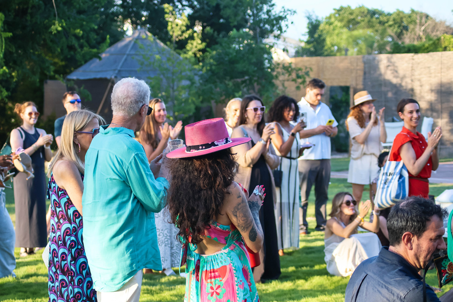 Guests applauding on the lawn during an evening launch gathering