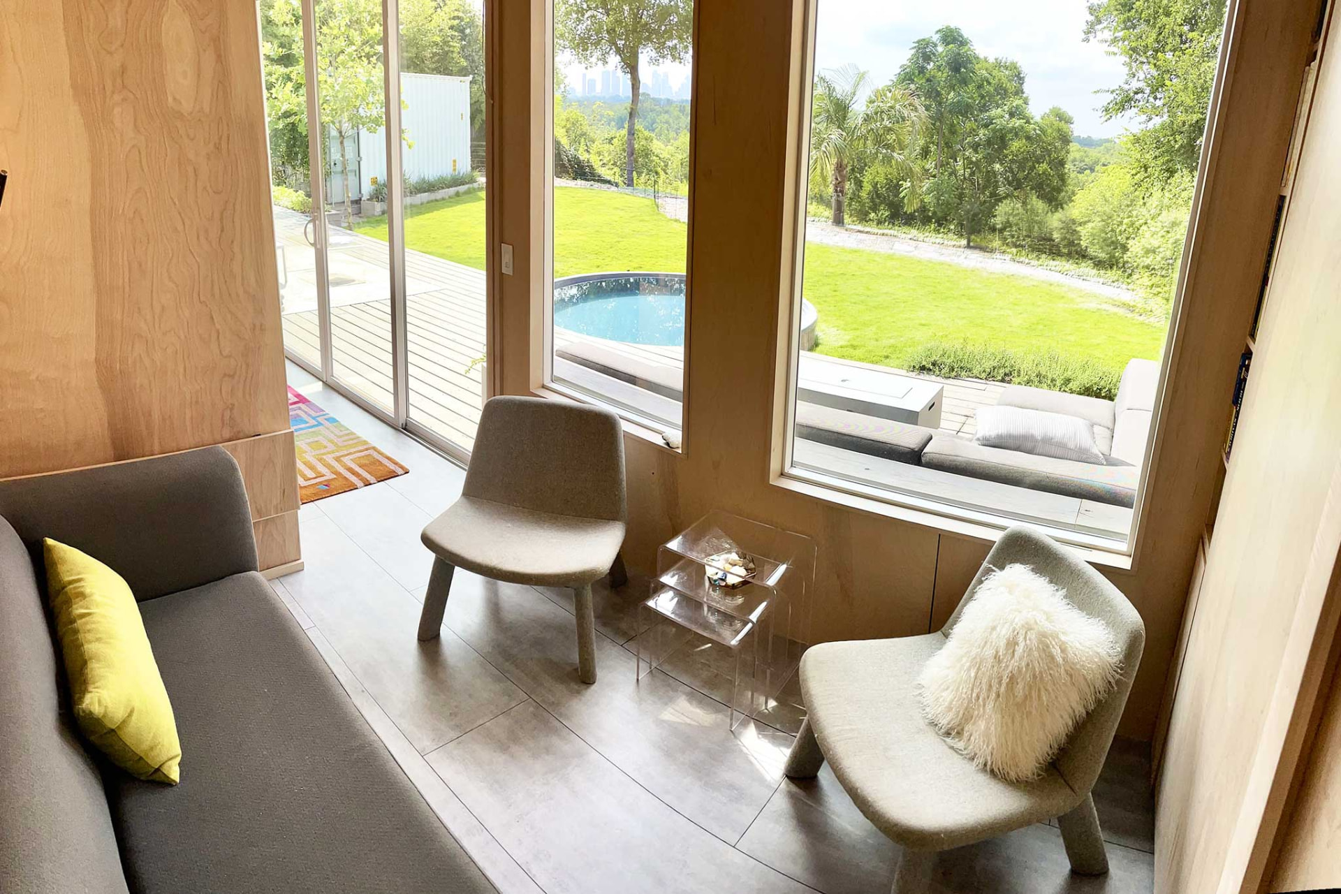 Smaller adjoining room with a daybed, two lounge chairs and corner windows onto the pool and lawn