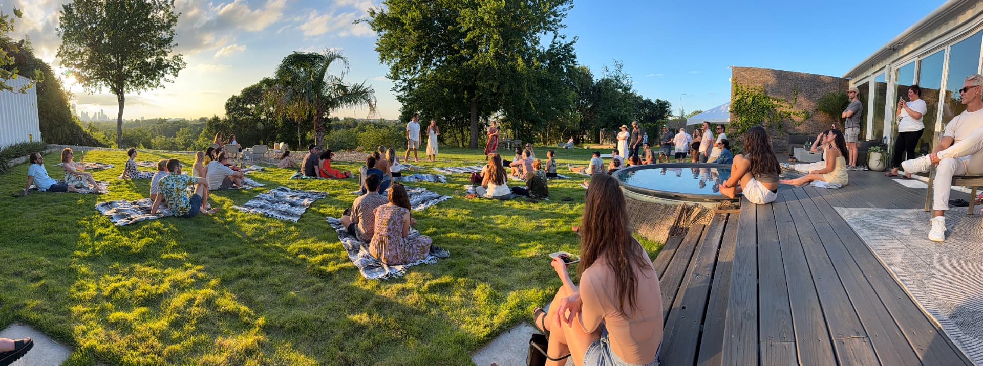 Guests seated across the lawn at golden hour beside the dipping pool, with the downtown Austin skyline on the horizon