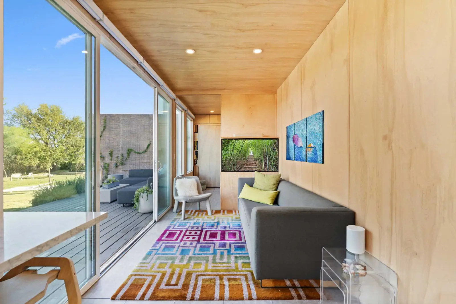 Lounge end of the Hub with a sofa, screen and sliding doors open to the deck seating and surrounding landscape