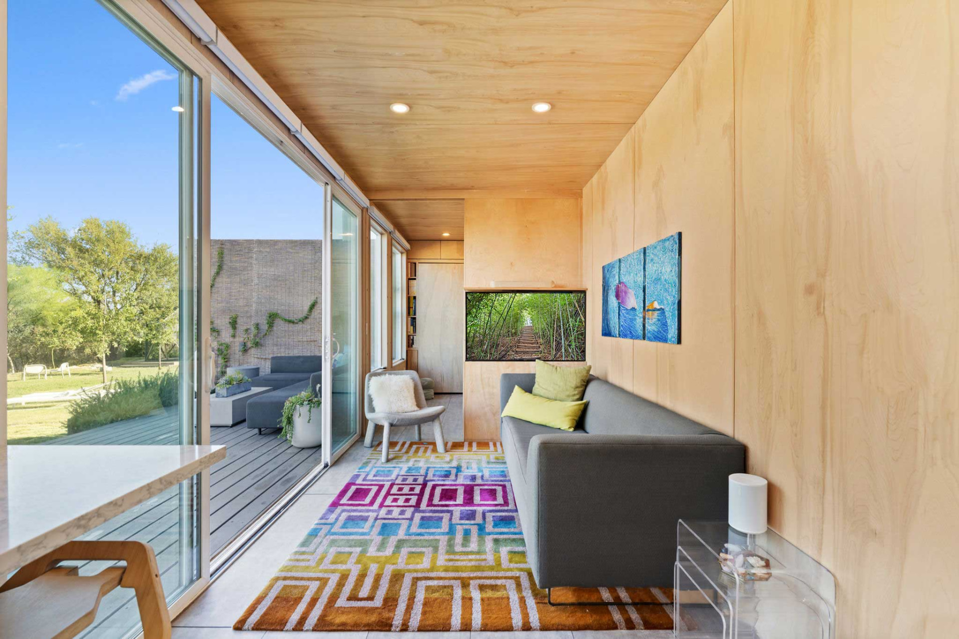 Lounge end of the Hub with a sofa, screen and sliding doors open to the deck seating and surrounding landscape