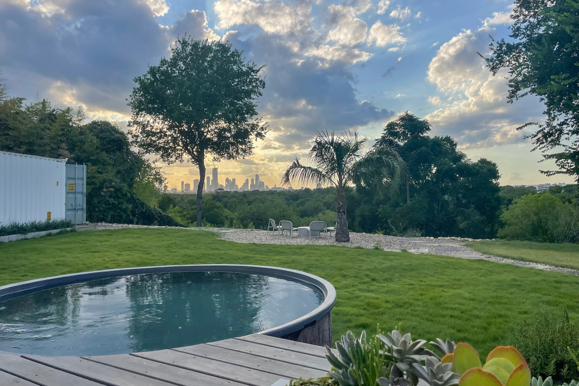 Dipping pool, deck, and open lawn with the downtown Austin skyline at dusk