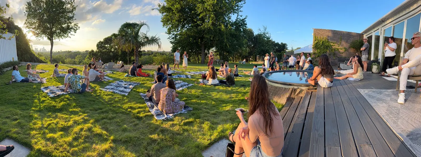 Guests seated across the lawn at golden hour beside the dipping pool, with the downtown Austin skyline on the horizon